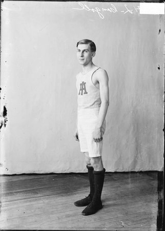 Basketball player H. L. Gongoll, standing in front of a light-colored backdrop in a room - Chicago Daily News, Inc.