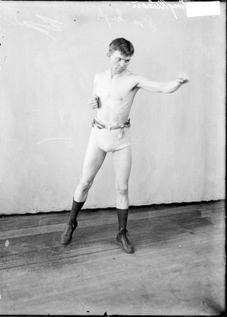 Pugilist Battling Nelson, throwing a left jab, standing in a boxing stance in front of a light-colored backdrop in a room - Chicago Daily News, Inc.