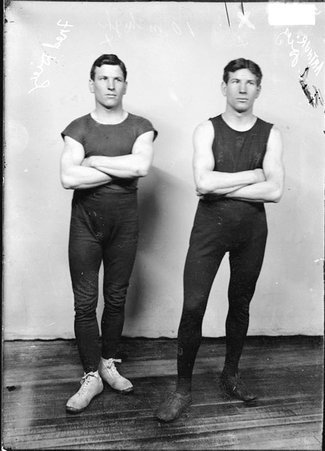 Wrestlers Fred Diez and Arthur Diez, standing in front of a light-colored backdrop in a room - Chicago Daily News, Inc.