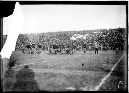 Football player holding the ball, running around tackled players on the field, Carlisle Indian School versus the University of Chicago - Chicago Daily News, Inc.