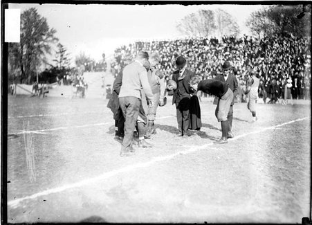 University of Chicago football team captain De Tray, standing with Illinois football players and referees during the coin toss - Chicago Daily News, Inc.