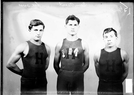 Wrestlers, Nick Dares, Sam Best and George Kareoris, standing in front of a light colored background in a room, text on image reads 15 - Chicago Daily News, Inc.