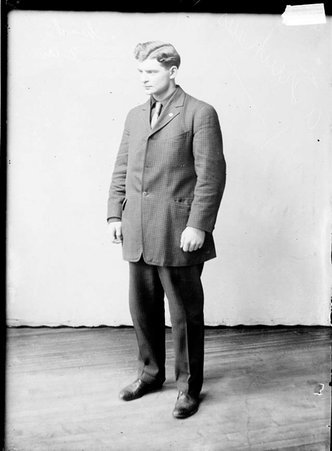 Football and baseball player, A. Trinkhaus, standing in front of a plain background in a room - Chicago Daily News, Inc.