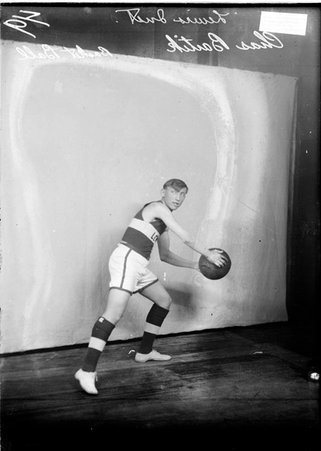 Basketball player, Lewis Institute, Bartik, holding a ball, leaning to his left standing in front of a backdrop - Chicago Daily News, Inc.