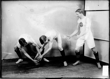 Basketball players Scott and James Cooke, struggling for possession of the basketball in front of a light colored background in a room - Chicago Daily News, Inc.