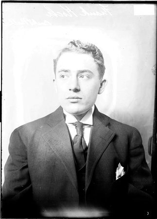 Basketball player, Frank Koch, wearing a suit, sitting in front of a backdrop - Chicago Daily News, Inc.