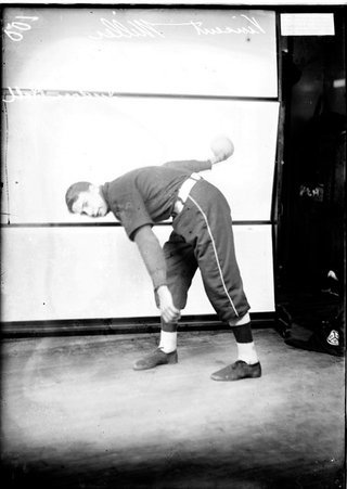 Pilsen Turner indoor baseball player, Vincent Miller, bending forward at the waist, holding a ball behind him in his right hand - Chicago Daily News, Inc.