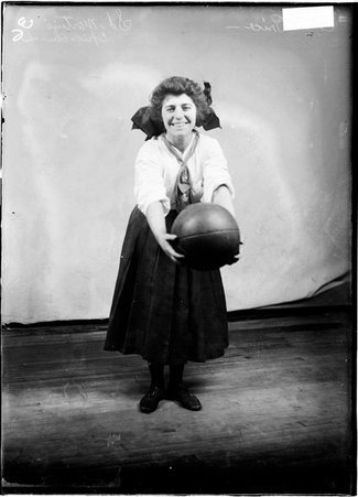 St. Martin Episcopal basketball player, Ella Price, bending forward holding a basketball in a room - Chicago Daily News, Inc.