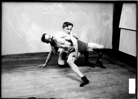 Wrestlers, Bredlau holding Thibodeaux's thigh from behind him in a room - Chicago Daily News, Inc.