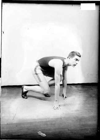 Lexington Ave. Baptist track team athlete, A. S. Clippinger, crouching in the starting position for a race in a room - Chicago Daily News, Inc.