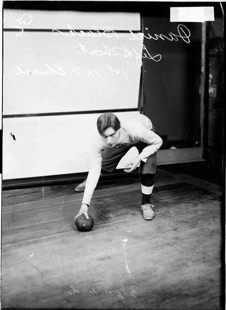 First Methodist Episcopal Church indoor baseball left shortstop Daniel Black, bending forward holding a ball on the floor - Chicago Daily News, Inc.