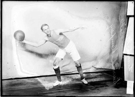Lincoln M. E. basketball player, Ewald Dempsey, holding a ball in his right hand in front of a light colored background in a room - Chicago Daily News, Inc.