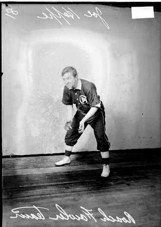 Indoor baseball player, Roach Fowler (team), Joe Hoppe, leaning forward, extending his hands, posing in front of a backdrop - Chicago Daily News, Inc.