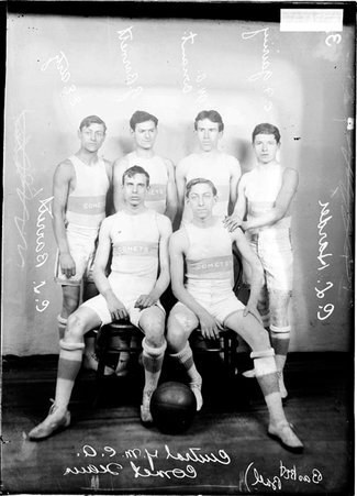 YMCA Comet basketball team players, Gairing, Conaut, Harder, C. L. Barrett, G. Barnett, and Urtz, standing in in a room - Chicago Daily News, Inc.