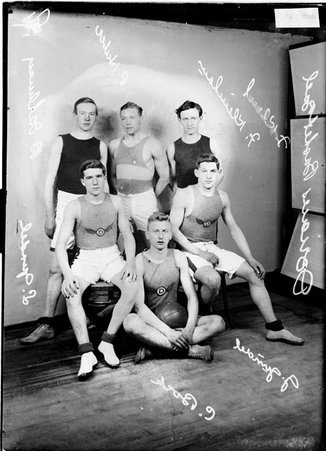 Dorian basketball team players H. Bock, B. Dahlman, L. Gundel, B. Huber, F. Kleinhaus and G. Gundel posing in front of a backdrop - Chicago Daily News, Inc.