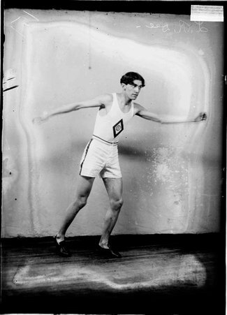 Runner, L. R. Dee, standing with his arms out to the side in front of a light colored background in a room - Chicago Daily News, Inc.