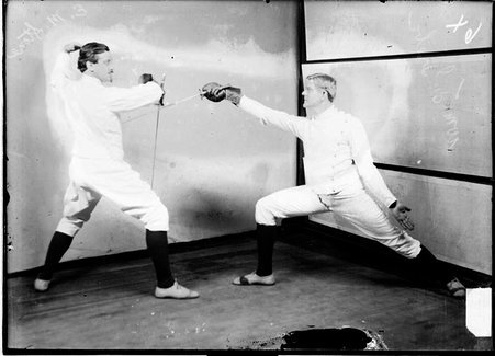 Fencers Edward Stone and William Grebe, posing in front of a backdrop, Stone is defending and Grebe is attacking - Chicago Daily News, Inc.