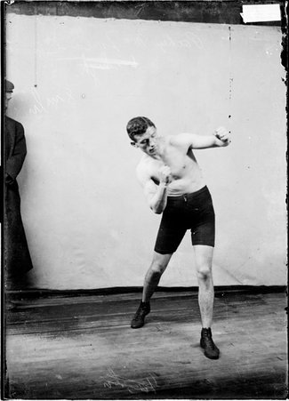 Pugilist, Packey McFarland, punching with his left arm standing in front of a light colored background in a room - Chicago Daily News, Inc.