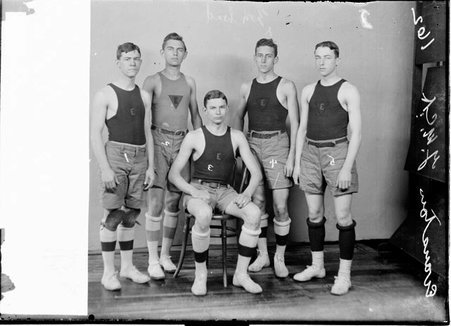 Evanston YMCA basketball team players E. Lamke, C. Plockman, G. Kreer, Lee and Collyer posing in front of backdrop - Chicago Daily News, Inc.