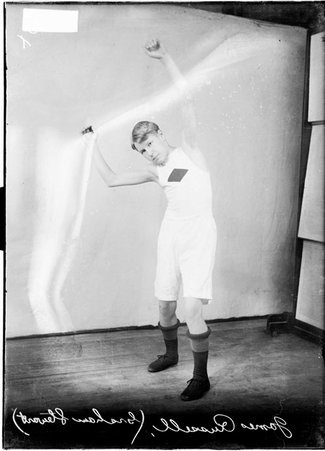 Graham Stewart athlete named James Russell, standing in a room with his arms above his head - Chicago Daily News, Inc.