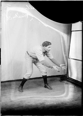 Austin Christian Church indoor baseball player, Max Llewellyn,standing in a room reaching with both arms out - Chicago Daily News, Inc.