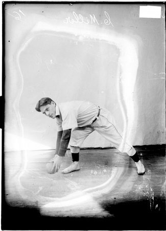 Austin Christian Church indoor baseball player, Charley Miller, lunging to the right, holding ball in both hands in a room - Chicago Daily News, Inc.