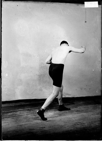 Pugilist, Packey McFarland, standing in a room, back to the camera punching with his right arm - Chicago Daily News, Inc.