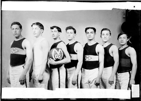 Basketball players, N. Reikert, L. Berger, S. Pinkus, A. Himmelblau, A. Freedman, M. Hoffman, and S. M. Gome, standing in a line in a room - Chicago Daily News, Inc.