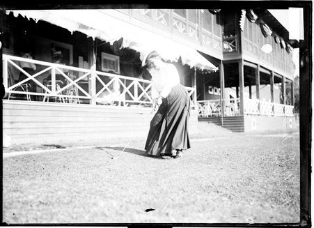 Golfer Mrs. B. M. Tunison, holding a golf club standing on the lawn near the clubhouse of Evanston Golf Club in Evanston, Illinois - Chicago Daily News, Inc.