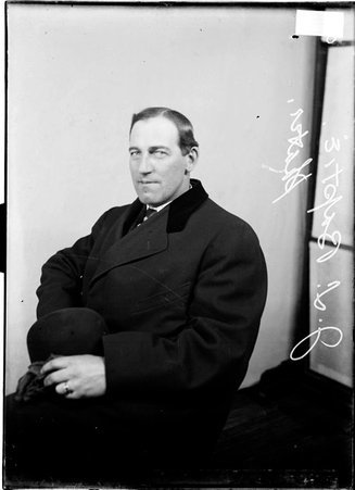 Roller skater J. L. Baptie, sitting in a chair in front of a light colored background in a room - Chicago Daily News, Inc.