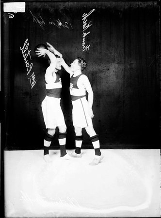 Christian Temple basketball players William Bartell and Frank Koch, standing in front of a dark backdrop - Chicago Daily News, Inc.