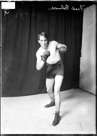 Pugilist Fred Gilmore, counterpunching with his left hand, standing in front of backdrops, light exposure - Chicago Daily News, Inc.