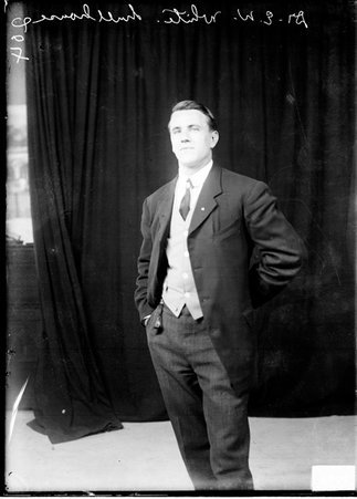 Hull House coach Dr. E. W. White, standing in front of a dark backdrop - Chicago Daily News, Inc.