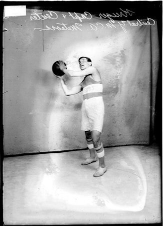 Central YMCA Meteors basketball captain and center Krueger, holding a basketball at shoulder level and leaning to his right - Chicago Daily News, Inc.