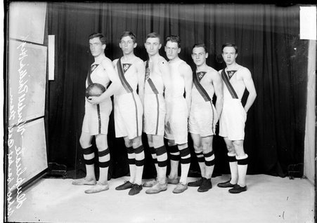 Wendell Phillips High School basketball players standing in front of a dark backdrop, dark exposure - Chicago Daily News, Inc.