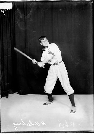 Fullerton Avenue Presbyterian indoor baseball player Harry Ackerburg, holding a bat, standing in batting stance in front of a backdrop - Chicago Daily News, Inc.