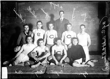 University of Chicago basketball players, kneeling and standing on mats in front of a brick wall in a room, light exposure - Chicago Daily News, Inc.