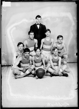 Central YMCA Meteors basketball team posing in front of a light-colored backdrop, dark exposure - Chicago Daily News, Inc.