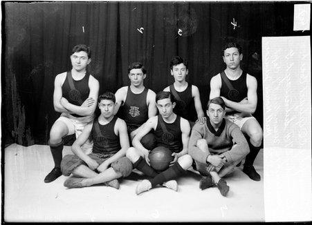 Hull House Juniors basketball players posing in front of a dark backdrop - Chicago Daily News, Inc.