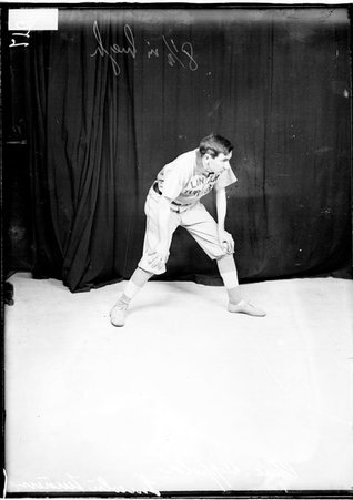 Lincoln Turners indoor baseball player Charles Dippold, leaning forward with his hands on his knees, standing in front of a backdrop - Chicago Daily News, Inc.