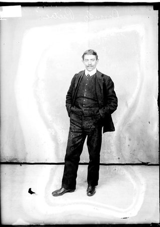 Runner Dorando Pietri, wearing a suit, standing in front of a light-colored backdrop - Chicago Daily News, Inc.