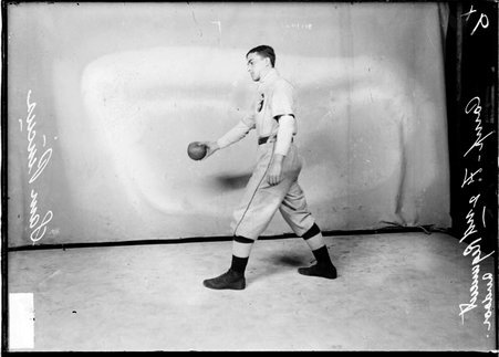 Company F 2nd Regiment indoor baseball player Sam Pincus, holding a baseball in his right hand, standing in profile by a backdrop - Chicago Daily News, Inc.