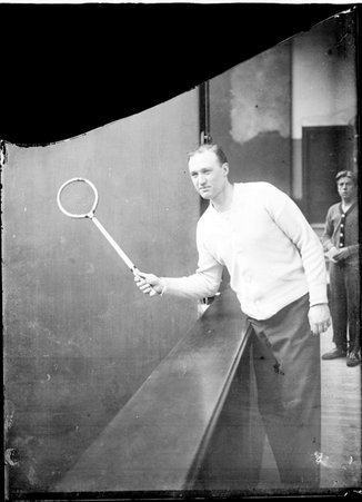 Racquetball player Homer Dixon, holding a racquetball racket, standing in a building - Chicago Daily News, Inc.