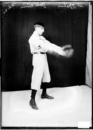 St. Ignatius baseball player John Kevin, holding his hands in front of him, standing in front of a dark backdrop - Chicago Daily News, Inc.