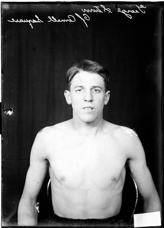 Cornell Square wrestler George Sturn, sitting shirtless in front of a dark backdrop - Chicago Daily News, Inc.