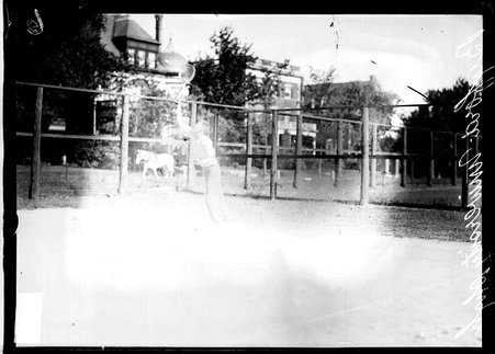 University High School tennis player Byford hitting a tennis serve, standing on a tennis court - Chicago Daily News, Inc.