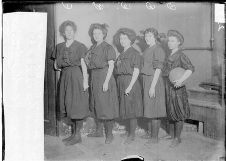 St. John's girls' basketball team members Gallaway, Told, Black, White, and Myers, standing in front of a dark backdrop - Chicago Daily News, Inc.