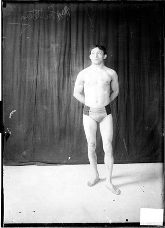 Wrestler Max Luttbeg, standing in front of a dark backdrop - Chicago Daily News, Inc.