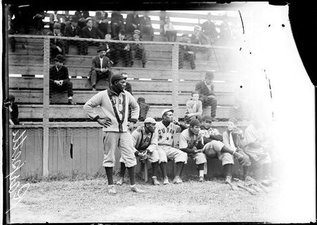 Cuban baseball player, Rarpeth, standing in front of a team bench and bleachers on a baseball field - Chicago Daily News, Inc.