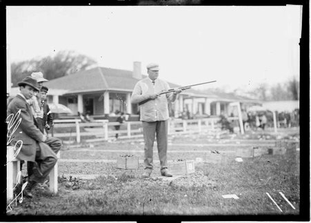 Shooter F. G. Bills holding a rifle, standing on the shooting range at the Chicago Gun Club - Chicago Daily News, Inc.